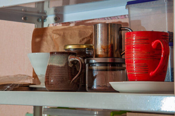 Various coffee mugs, a jar of coffee grounds, and other kitchen items are neatly arranged on a metal shelf