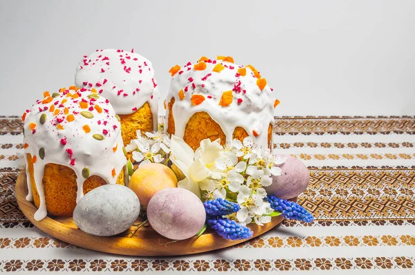 Şenlikli bir Paskalya sofrası, renkli yumurtalar ve desenli masa örtüsü üzerindeki narin bahar çiçekleriyle çevrili özenle dekore edilmiş kulich kekleri içerir.