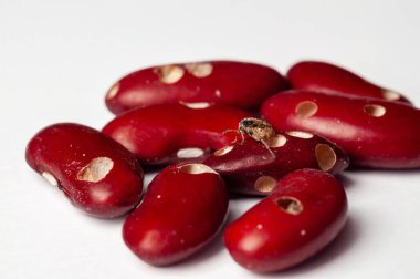 Kırmızı böbrek fasulyelerine yakın plan, beyaz yüzeyde fasulye bitleri zarar görmüş, potansiyel tarım sorunları ve gıda güvenliği sorunlarını vurguluyor..