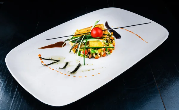Ensalada de verduras decoradas con rollos rellenos de masa servidos en un plato blanco — Foto de Stock