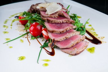 Orta az pişmiş biftek bir tabakta sebze ve peynir ile servis