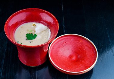 Siyah ahşap bir masa kırmızı bir bardakta servis sebze çorbası