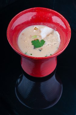 Siyah ahşap bir masa kırmızı bir bardakta servis sebze çorbası