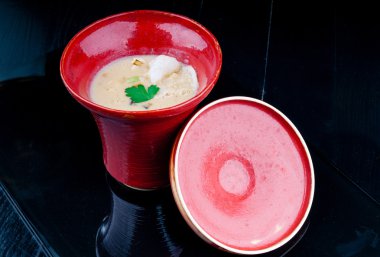 Siyah ahşap bir masa kırmızı bir bardakta servis sebze çorbası