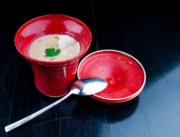 Zeleninová polévka, podávaná v červené cup na černý dřevěný stůl — Stock fotografie