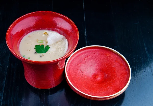 Siyah ahşap bir masa kırmızı bir bardakta servis sebze çorbası