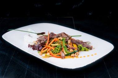 Kıyılmış et ile birlikte beyaz bir tabakta sebze