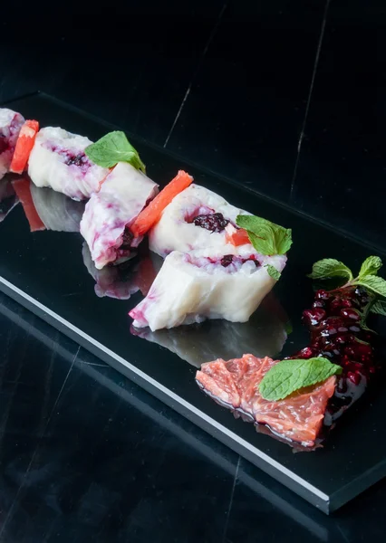 Rollos de sushi dulce con mora servido en un plato negro — Foto de Stock