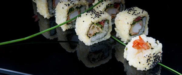 Sushi uramaki en un plato negro — Foto de Stock