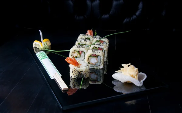 Sushi uramaki en un plato negro — Foto de Stock