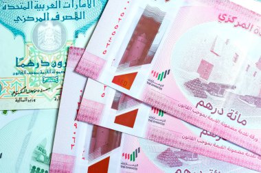 Birleşik Arap Emirlikleri para biriminin (AED) yüksek kaliteli, tepeden tırnağa bir görüntüsü, renkli Emirati banknotları ve gümüş Dirham paralarının karışımı. Resimde BAE Dirham 'ın yerel kültür sembolleri ve portresi de dahil olmak üzere ayrıntılı tasarımı yer alıyor.