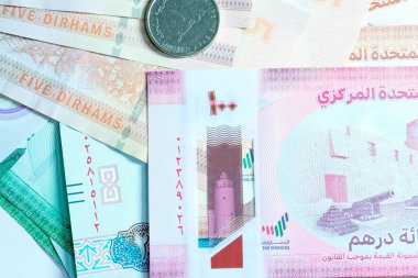 Birleşik Arap Emirlikleri para biriminin (AED) yüksek kaliteli, tepeden tırnağa bir görüntüsü, renkli Emirati banknotları ve gümüş Dirham paralarının karışımı. Resimde BAE Dirham 'ın yerel kültür sembolleri ve portresi de dahil olmak üzere ayrıntılı tasarımı yer alıyor.