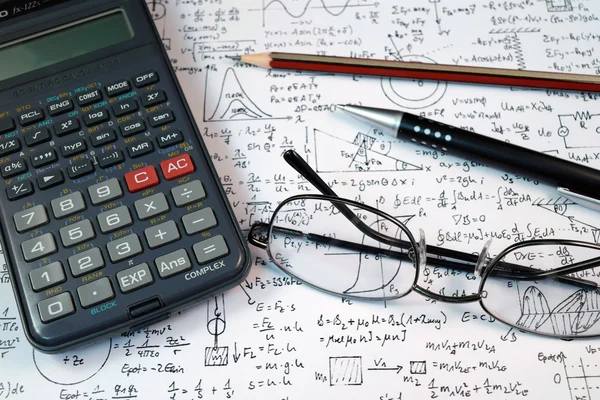 Bril, pen en potlood over de formule met calculator — Stockfoto