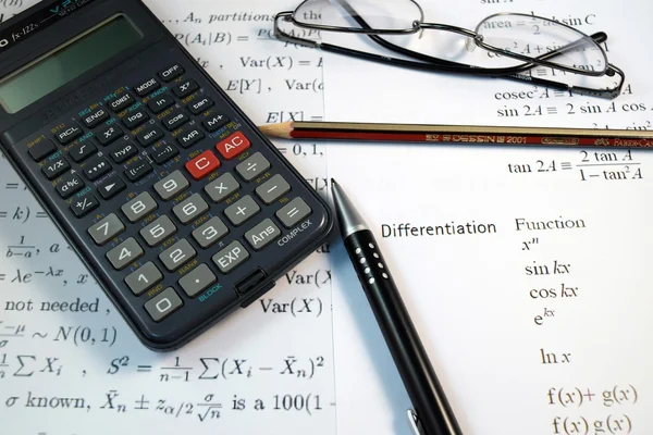 Brýle, pera a tužky nad vzorec s kalkulačkou — Stock fotografie