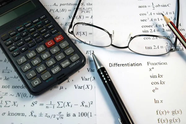 Bril, pen en potlood over de formule met calculator — Stockfoto