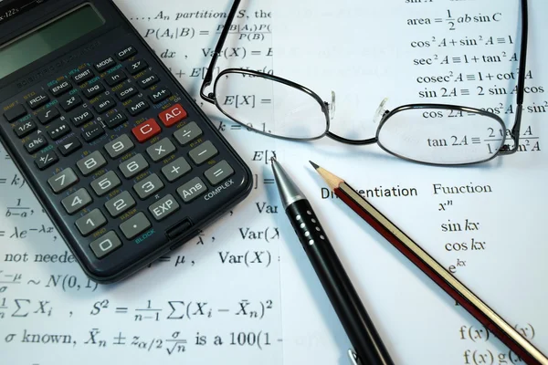 Gözüne gözlük, kalem ve kurşun kalem formülü ile hesap makinesi üzerinde