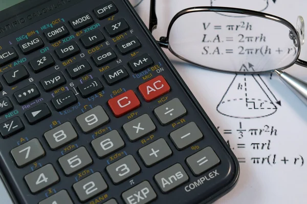 Очки, ручка и карандаш над формулой с калькулятором — стоковое фото