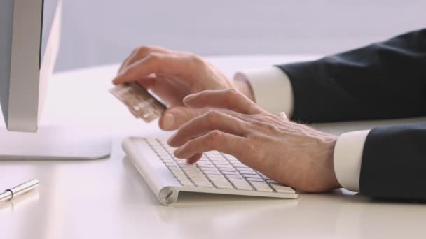 Mãos masculinas segurando um cartão de crédito em um teclado durante compras online . — Vídeo de Stock