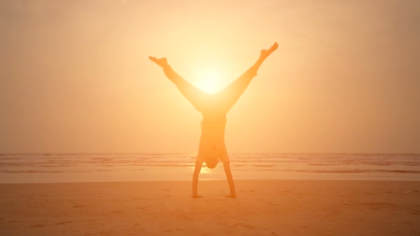 Člověk dělá jógu při západu slunce na pláži — Stock video