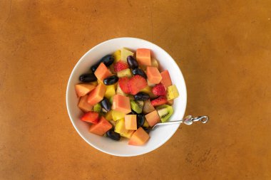 Taş zemin üzerine beyaz kase meyve salatası. Üstten Görünüm