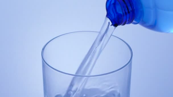 Gießen von Wasser aus der Flasche in Glas in blauer Tonung — Stockvideo