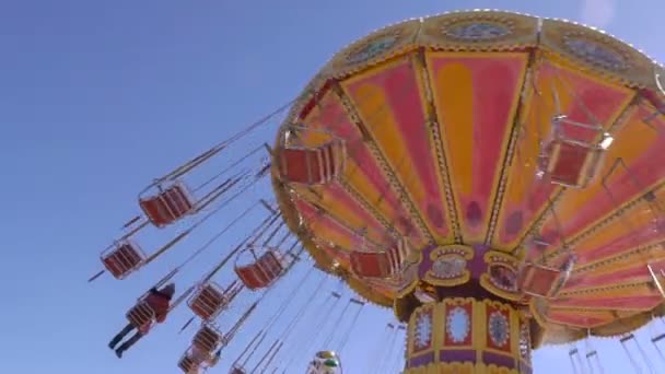 Kleurrijk carrousel in beweging over blauwe hemel — Stockvideo