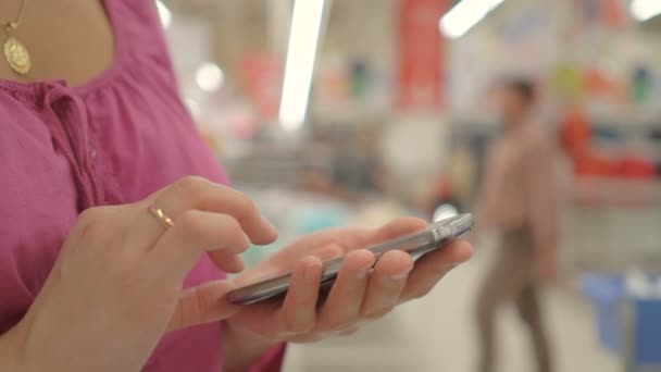 Vrouw met behulp van de telefoon in de winkel — Stockvideo