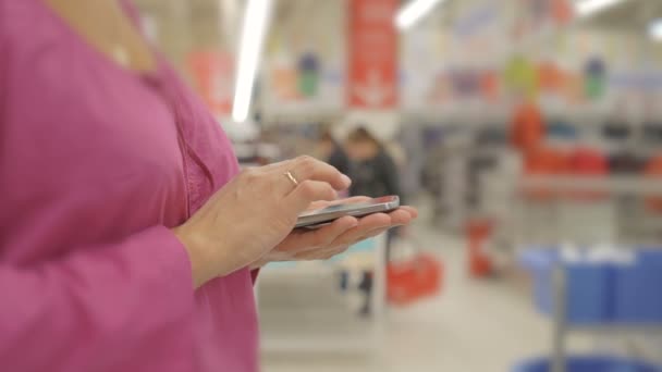 Manos de mujer usando el teléfono móvil en la tienda departamental  : — Vídeos de Stock