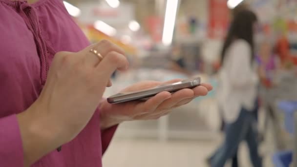 Mulher usando telefone celular em mãos de supermercado close-up . — Vídeo de Stock