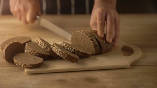 Χέρια κοπής ψωμιού με μαχαίρι σε ρουστίκ ξύλινα πίνακα — Αρχείο Βίντεο