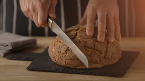 Chef hands slicing home-made bread on wooden table — Stock Video