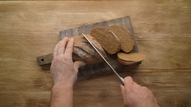 Volkoren brood snijden op houten tafel, top uitzicht, — Stockvideo