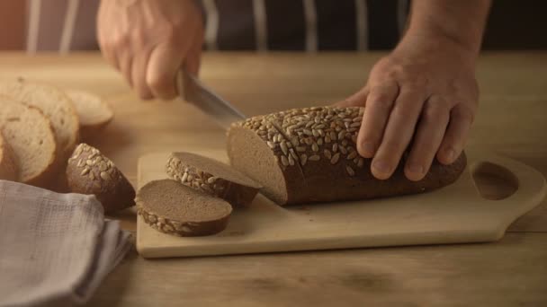 Close-up van chef-kok bezuinigingen brood op tafel met een mes — Stockvideo