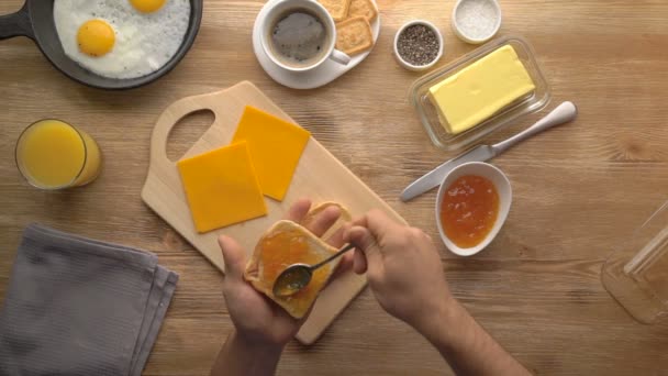 Mannelijke handen voorbereiding ontbijt toast met jam, bovenaanzicht — Stockvideo