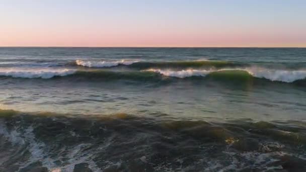 Bei Sonnenaufgang dicht über den Meereswellen am Strand entlang fliegen — Stockvideo