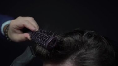 Kuaför saç kurutma makinesi ve saç fırçasıyla stil yapıyor.