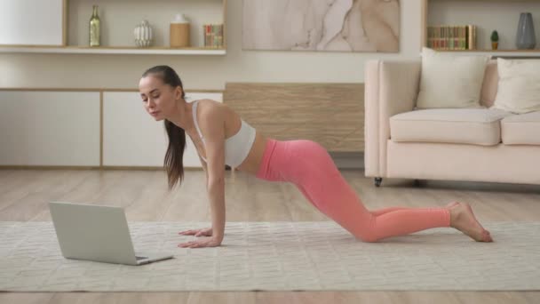 Evde laptopçu arayan çok ırklı çekici bayan evde yoga yapıyor meditasyon yapıyor ve rahatlıyor, ev konseptinde sağlık ve egzersiz yapıyor COVID-19 salgını nedeniyle kendini izole ediyor. — Stok video