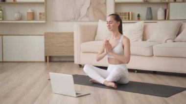 Genç spor formundaki zayıf yoga öğrencisi internetteki internet öğretmeniyle dizüstü bilgisayar konuşmalarında konferans görüntüsü görüşmesi yapıyor. Web kamerası eğitim zihinsel terapi kavramı