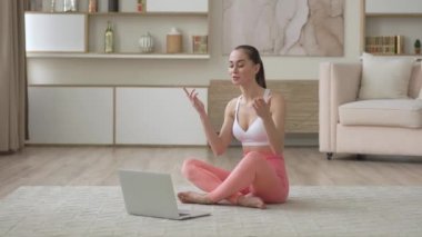 Kadın internet yoga öğretmeni ev konuşmalarıyla uzaktan sohbet ediyor. Web kamerasıyla uzak mesafeler açıyor. Video konferans görüşmesi yapıyor, webinar eğitimi, sağlık ve egzersiz yapıyor.