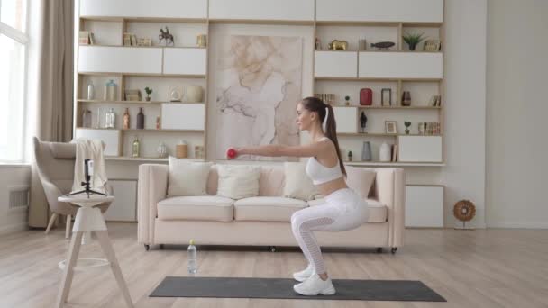 Formda genç bir kadın evde kalas egzersizi yapıyor. Aktif sağlıklı kız pilates yoga antrenmanını laptopta yoga minderinde gerinerek video dersini izlemekten hoşlanıyor.. — Stok video