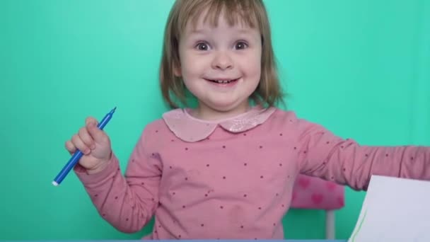 Roztomilý opustil usmívající se holčička z 2 let proti zelenému pozadí — Stock video