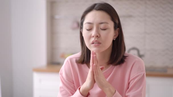 Mladá Asiatka se modlí s nadějí a drží se za ruce. Dívka přemýšlející s namaste mudra gestem a zavřenýma očima. Duchovní náboženské dospívající dívka říká modlitební koncept, zblízka pohled — Stock video