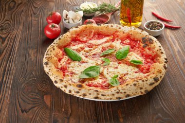 Eritilmiş mozzarella peynirli orijinal İtalyan Napoli pizzası, taze fesleğen yaprağı ve ahşap masa üzerine domates sosu. Fast food İtalyan menüsü ve vejetaryen yemek konsepti
