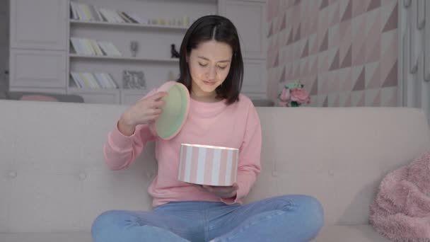 Feliz espantado jovem multi étnico asiático mulher abrindo a caixa de presente com surpresa sentado no sofá em casa — Vídeo de Stock