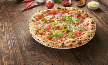 Parma jambonlu ve ahşap zemin üzerinde taze roka bulunan orijinal İtalyan Napoli pizzası. Fast food yeme konsepti