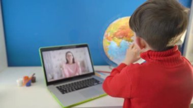 Evde eğitim gören bir çocuk dizüstü bilgisayarla evde coğrafya öğreniyor. Akıllı çocuk video dersi izliyor ve ödev yapıyor. Uzaktan eğitim, Skype öğretmeniyle online öğrenim