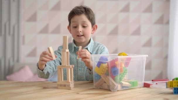 幸せなかわいい白人の男の子が木造ブロックからゲーム構築コンストラクタータワーをプレイし、就学前の子供は自宅で楽しんで、子供の発達、遊びのコンセプト — ストック動画