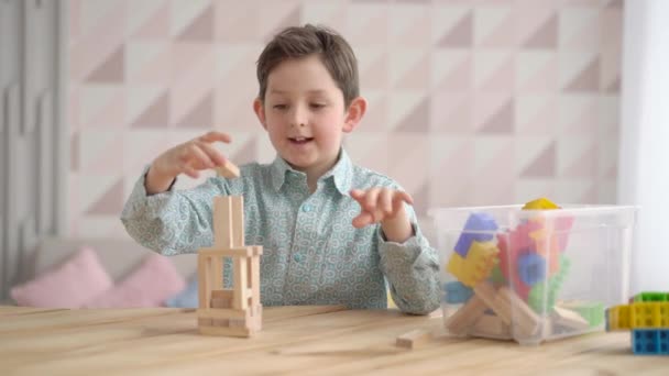 Ευτυχισμένο χαριτωμένο μικρό καυκάσιο αγόρι παίζει παιχνίδι κτίριο κατασκευαστού πύργου από ξύλινα μπλοκ, προσχολικής ηλικίας παιδί που διασκεδάζουν στο σπίτι, την ανάπτυξη του παιδιού, την έννοια του χρόνου παιχνιδιού — Αρχείο Βίντεο