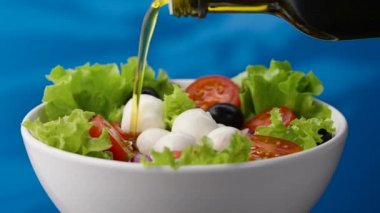 Taze ev yapımı vejetaryen salatasına zeytin yağı dök. Mozarella peyniri ve kiraz domatesli sağlıklı sebze salatası, sağlıklı öğle yemeği, sağlıklı beslenme, diyet vegan gıda konsepti.