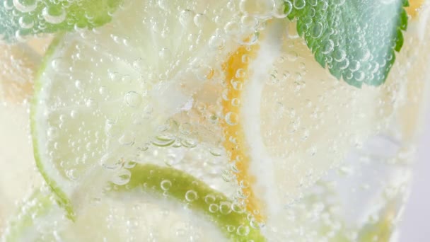 Macro refreshing soda tonic fizzy sparkling water, lime in glass, ice cubes. Slice of lemon, mineral bubbles. Healthy, dietary nutrition. Cold lemonade mojito cocktail twinkling carbonated soft drink — Stock Video